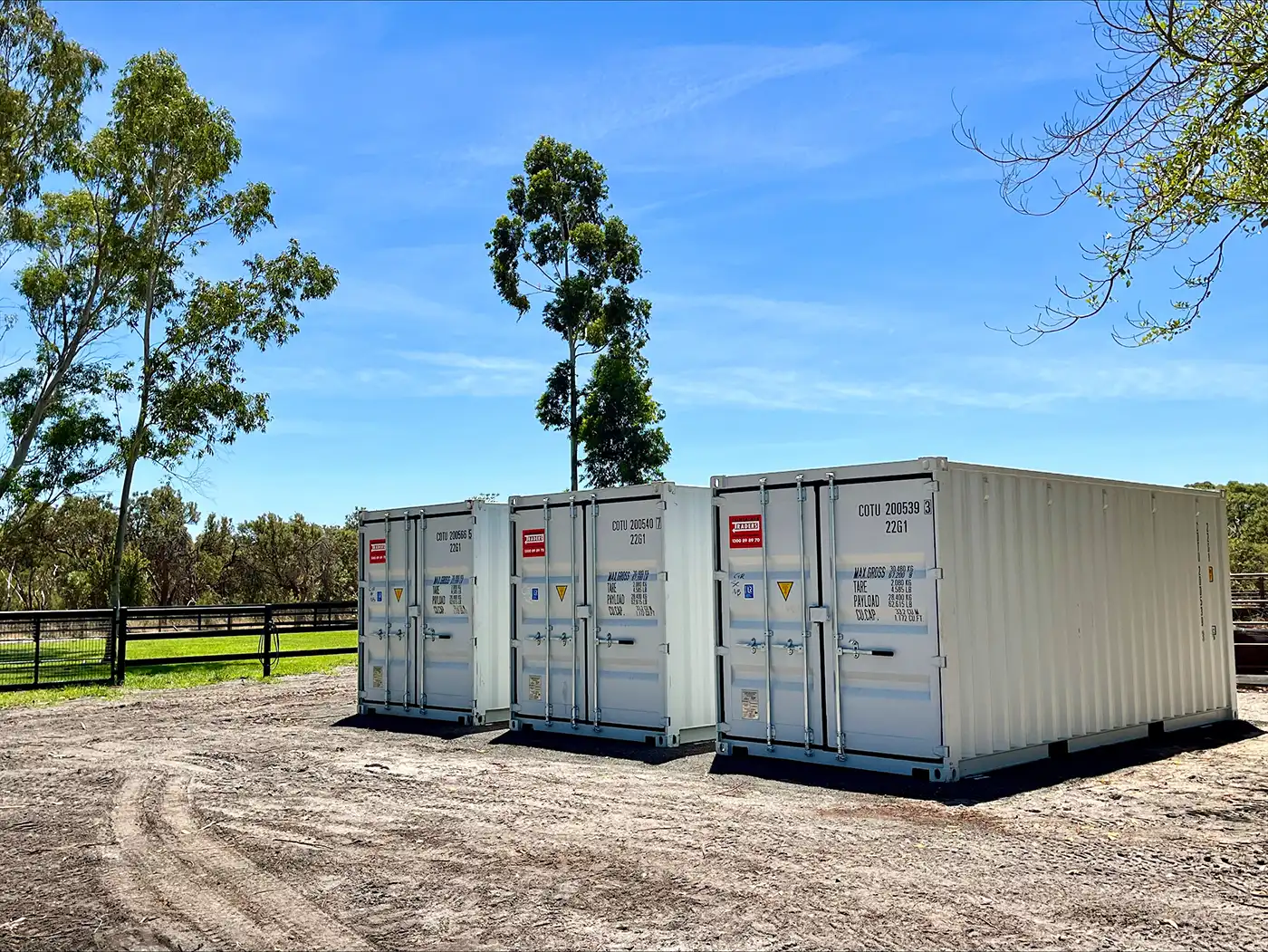 Three branded 20ft shipping containers from Container Traders positioned side by side on a rural farm property.